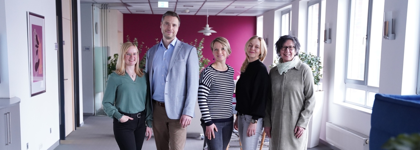 Vier Frauen und ein Mann stehen nebeneinander und schauen in die Kamera