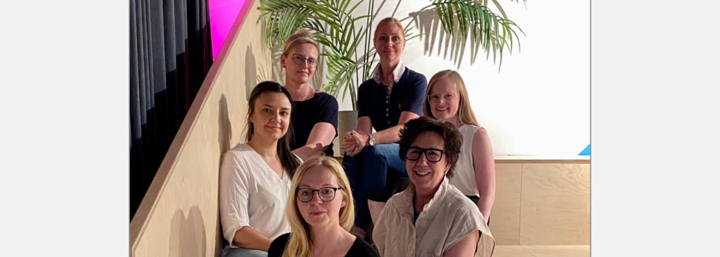 Sechs Frauen sitzen auf einer Holztreppe.