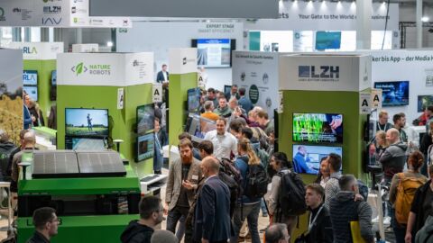 Viele Menschen unterhalten sich an einem Messestand.
