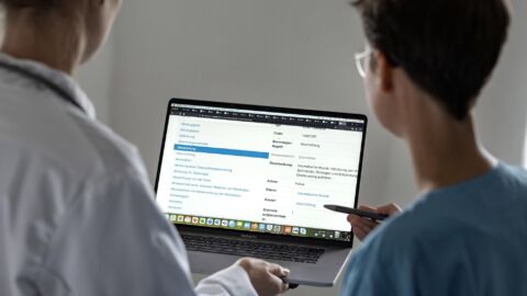 Zwei Personen schauen auf einen Laptop, auf dem eine Online-Umfrage zu sehen ist.