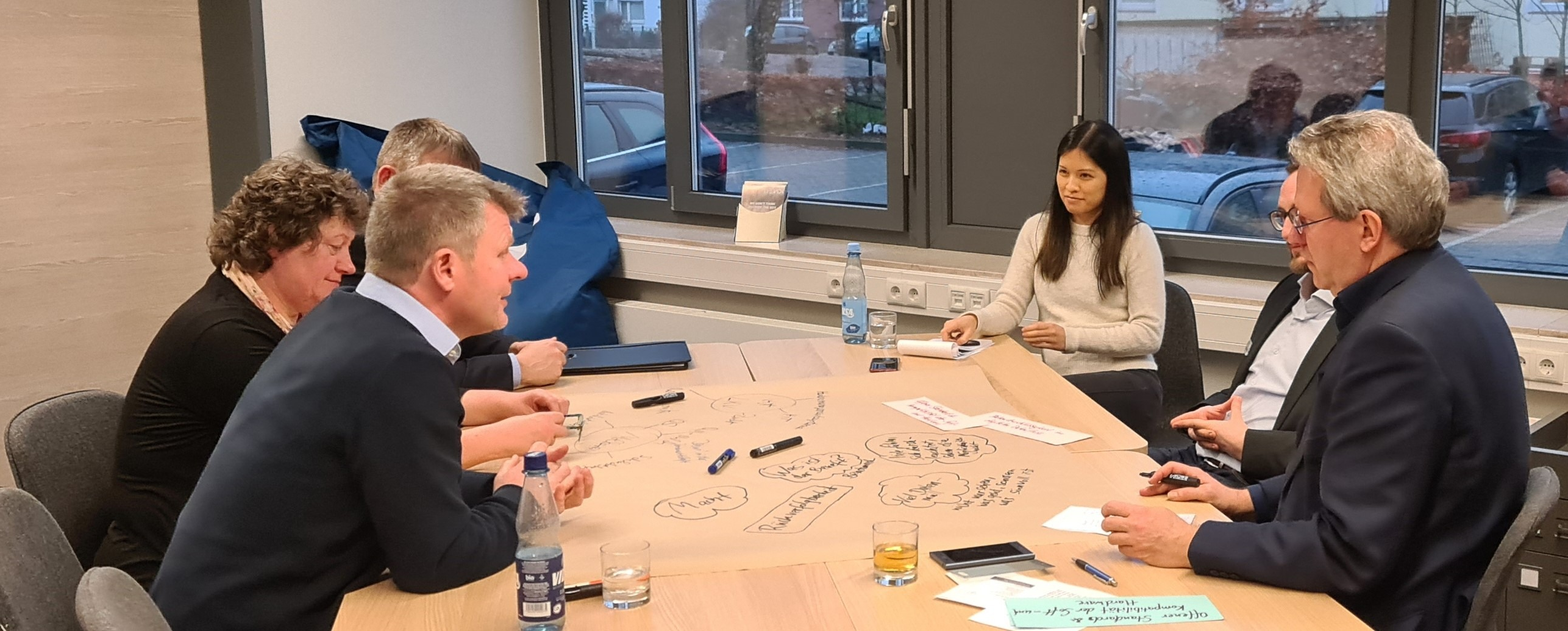 Mehrere Menschen sitzen an einem Tisch und bearbeiten Plakate