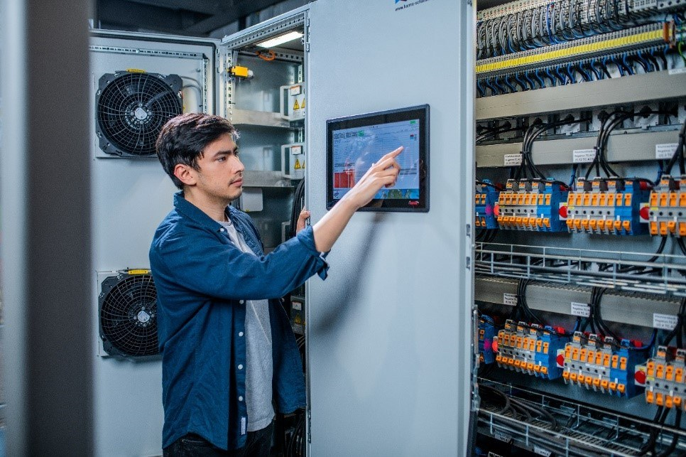 Mann steht in Technikraum und bedient einen Bildschirm