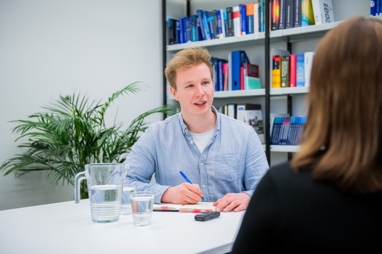 Zwei Personen sitzen an Tisch und sprechen