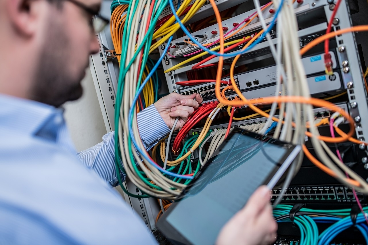 Ein Mann bearbeitet einen Server mit Kabeln und Knöpfen