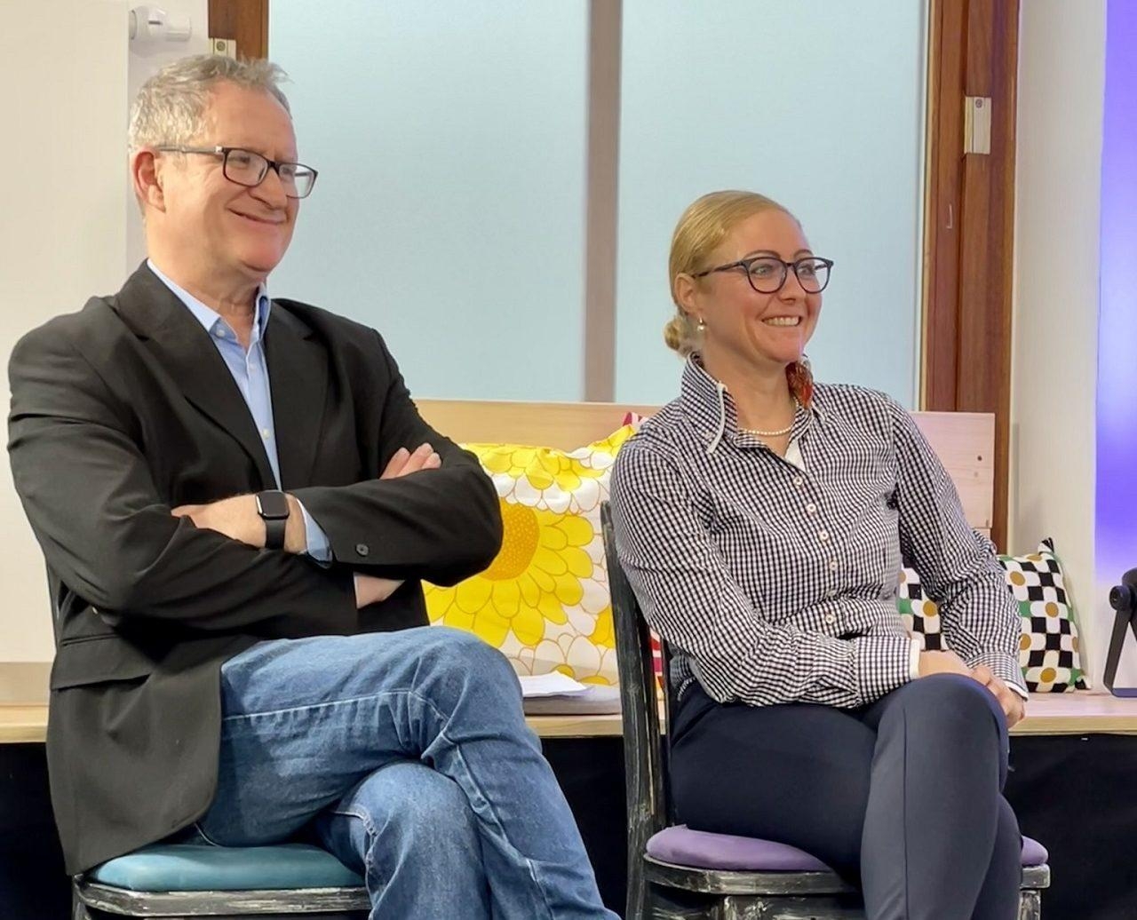 Eine Frau und ein Mann sitzen nebeneinander und lachen.