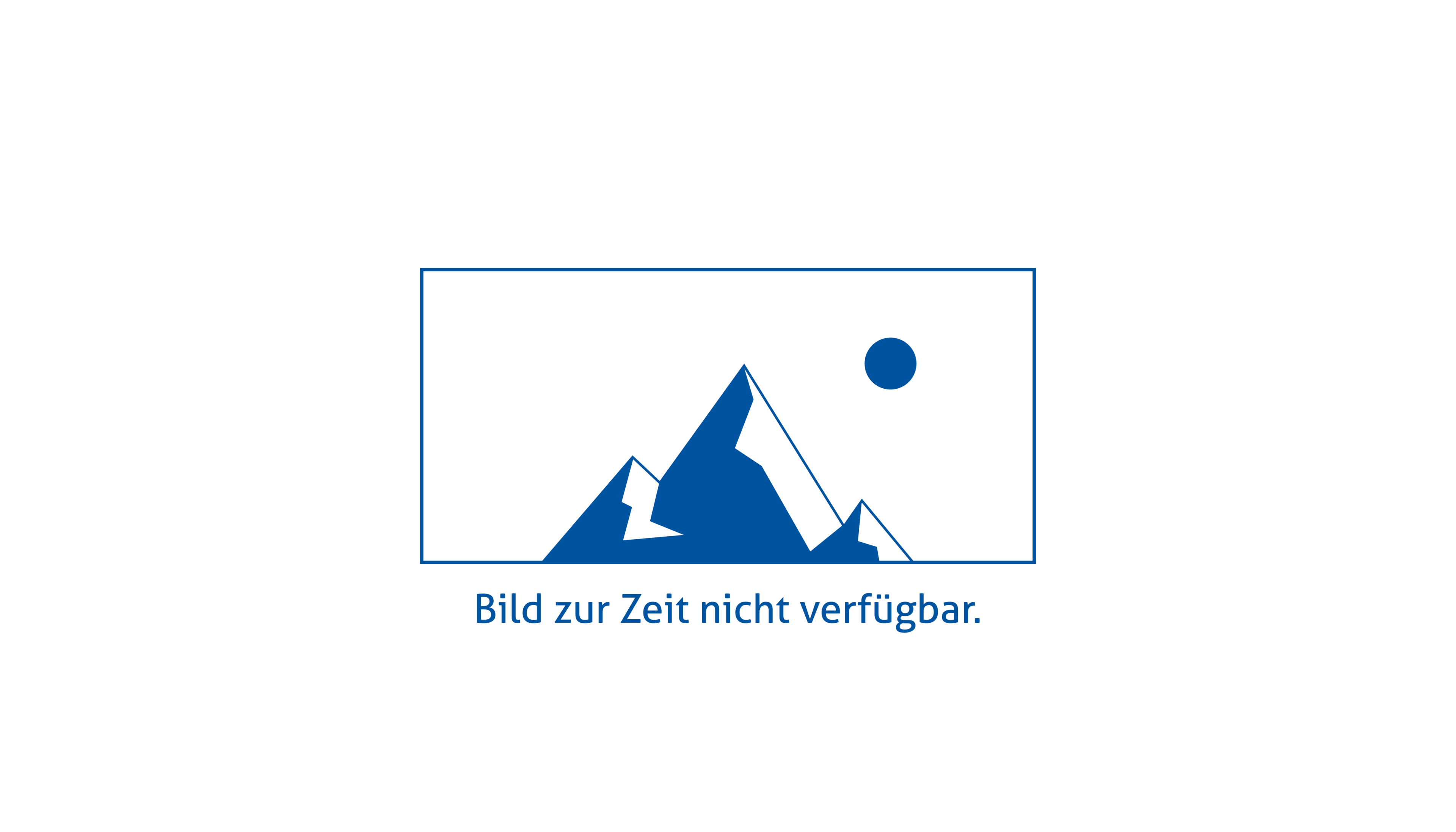 Frau sitzt an Tisch und bedient einen Laptop