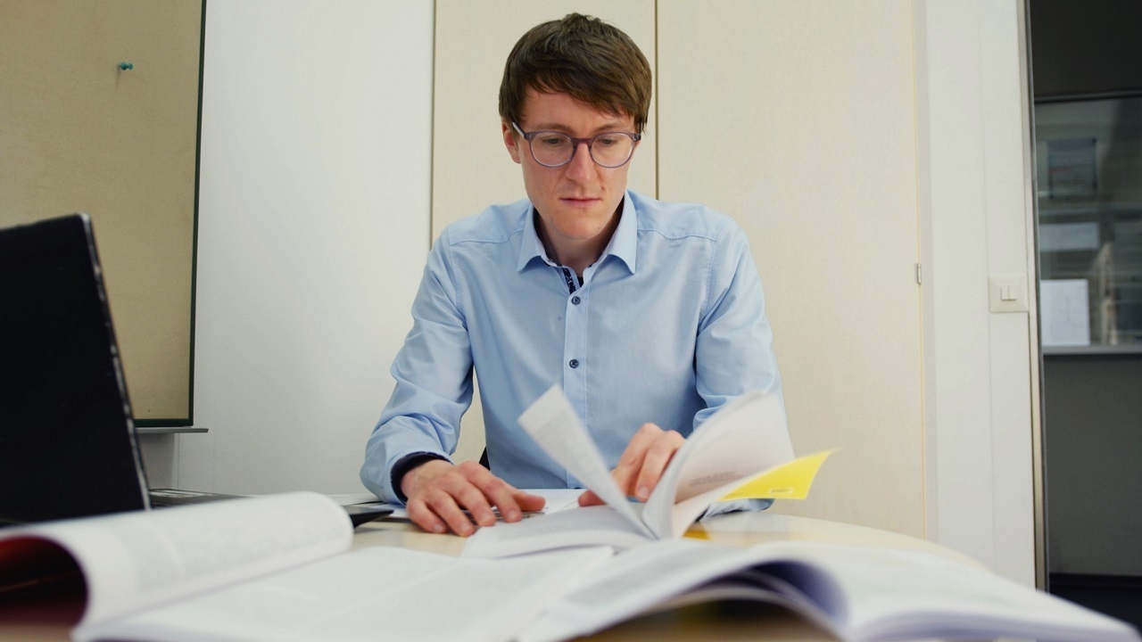 Ein Mann sitzt vor offenen Büchern.