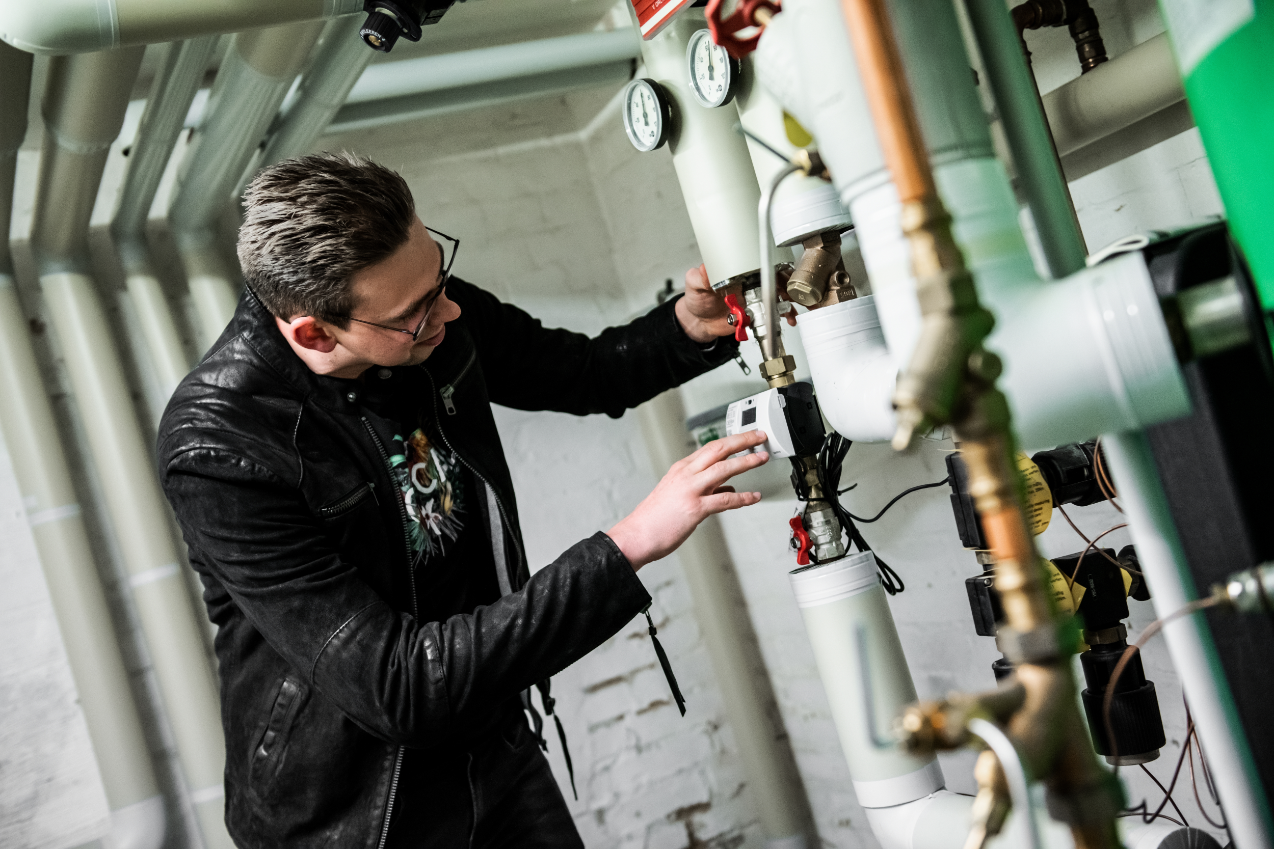 Mann schaut sich Zählerstand bei Rohrleitung an