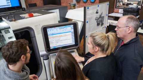 Mehrere Personen stehen vor einem Bildschirm