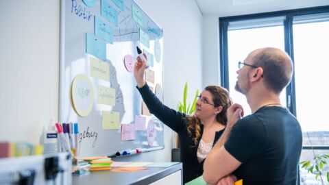 Zwei Menschen betrachten Post-It Wand