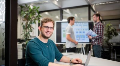 Mann sitzt am Tisch und bedient Laptop