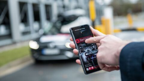 Ein Handy wir vor einem Auto stehend bedient