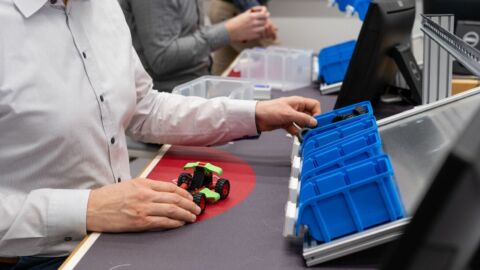 Person bastelt an kleinem Modellfahrzeug mit Rädern