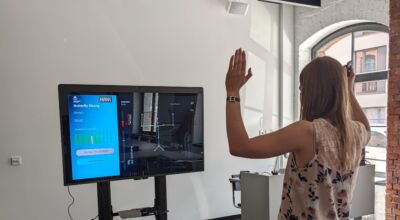 Frau steht vor Bildschirm und interagiert mit diesem