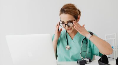 Frau aus medizinischem Beruf sitzt an Laptop