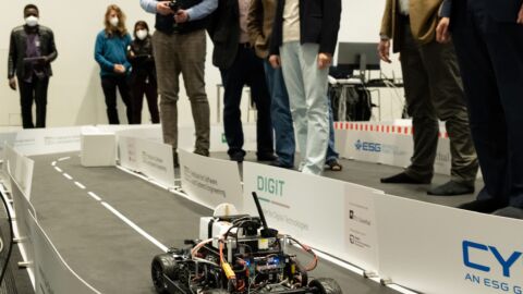 Beobachter stehen um einen Rennstrecke mit einem Modellauto herum