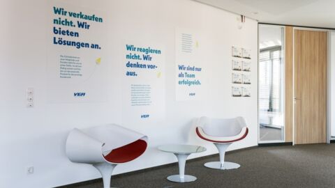 Moderne Stühle vor verschiedenen Plakaten.