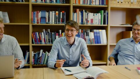 Männer sitzen an Tisch und lachen