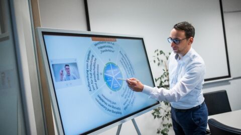 Mann zeigt etwas auf einem Bildschirm