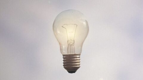 Hand unter einer schwebenden Glühlampe