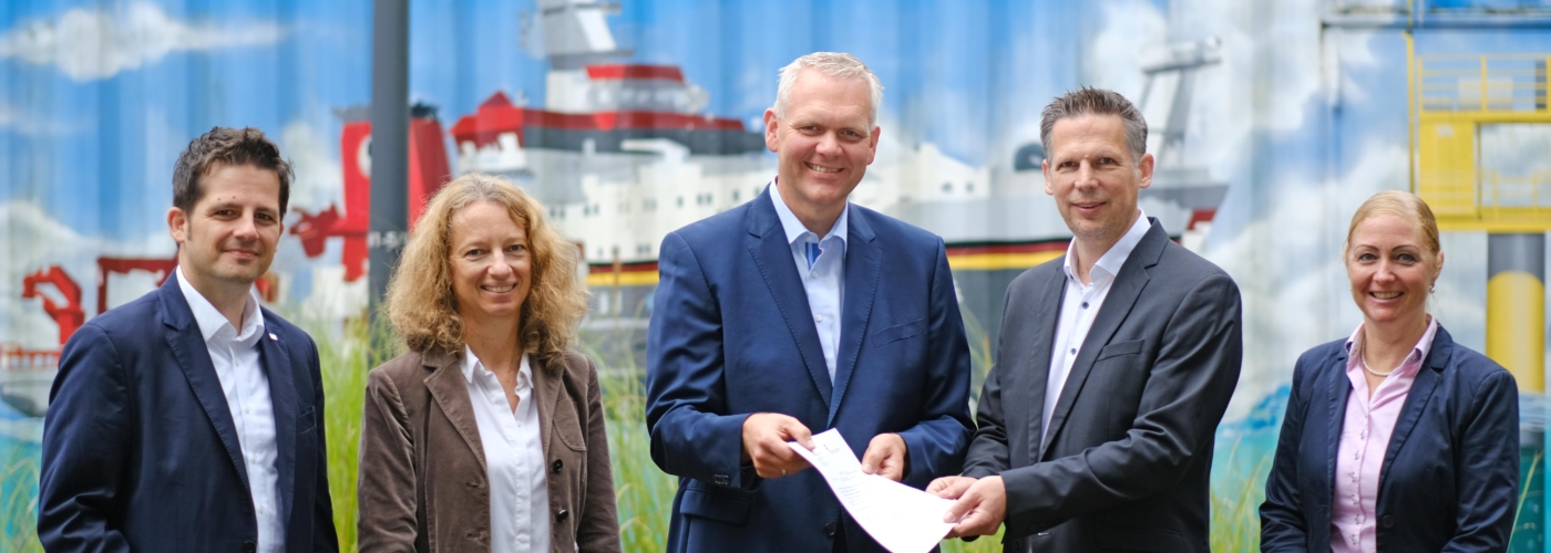 Fünf Personen blicken in die Kamera und lächeln.