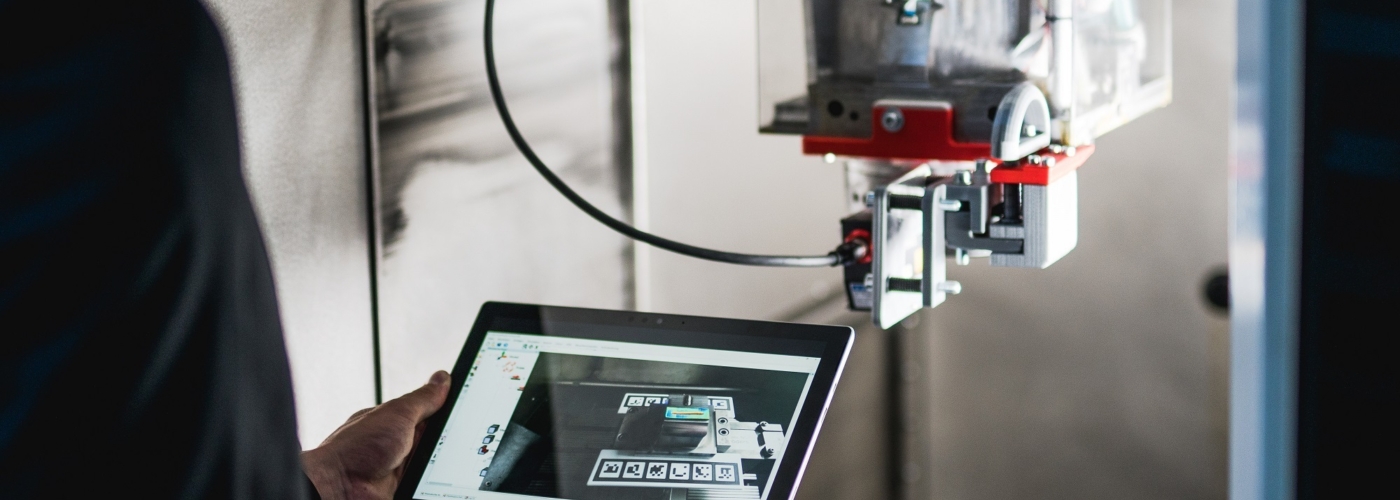Mann steht mit Tablet vor einer Maschine
