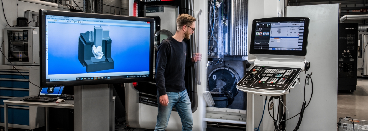 Eine Person steht vor einer großen Maschine mit Monitor