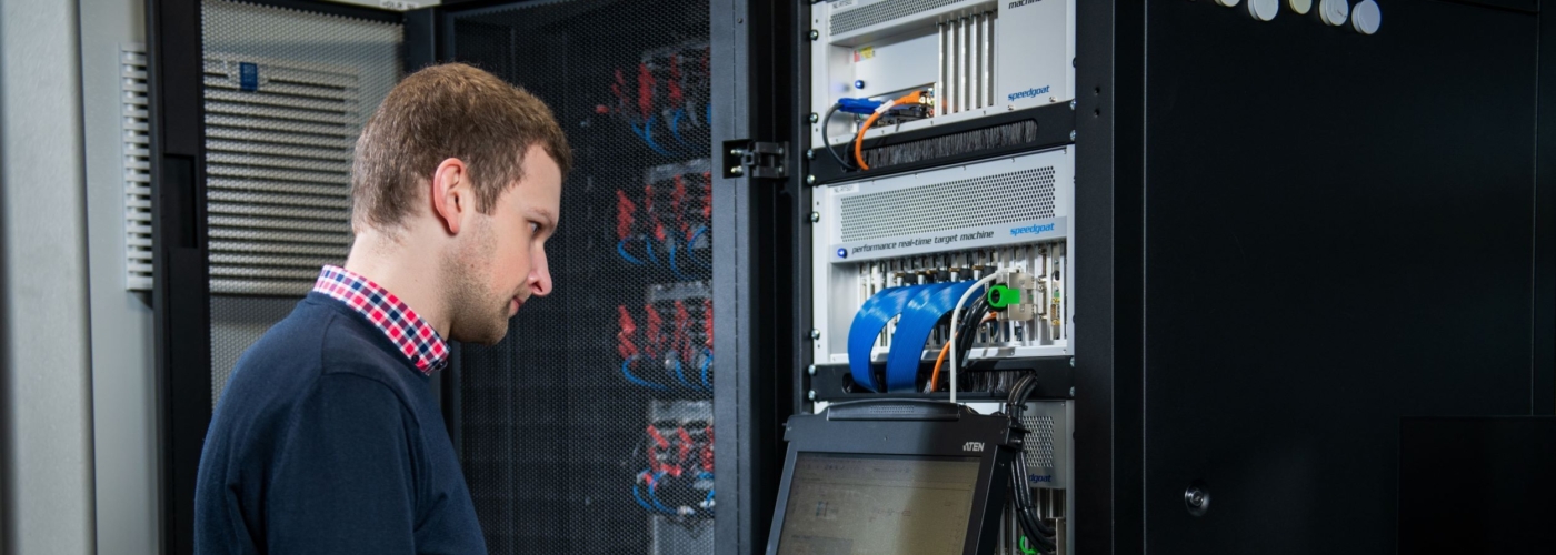 Mann steht bei einem Server und tippt etwas in die Tastatur