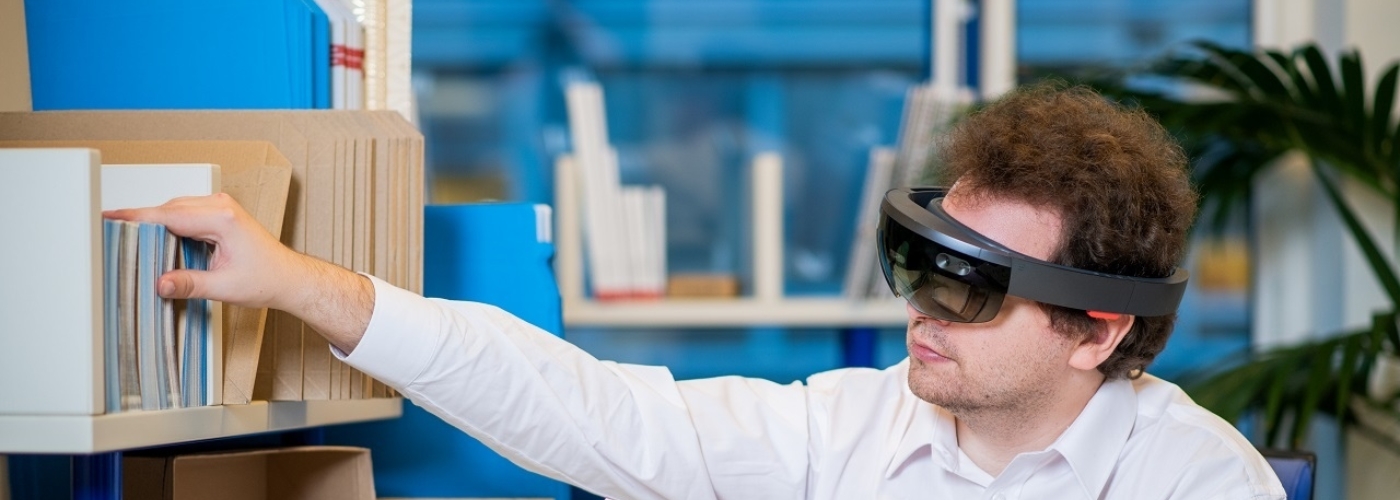 Mann mit AR-Brille sitzt an Schreibtisch