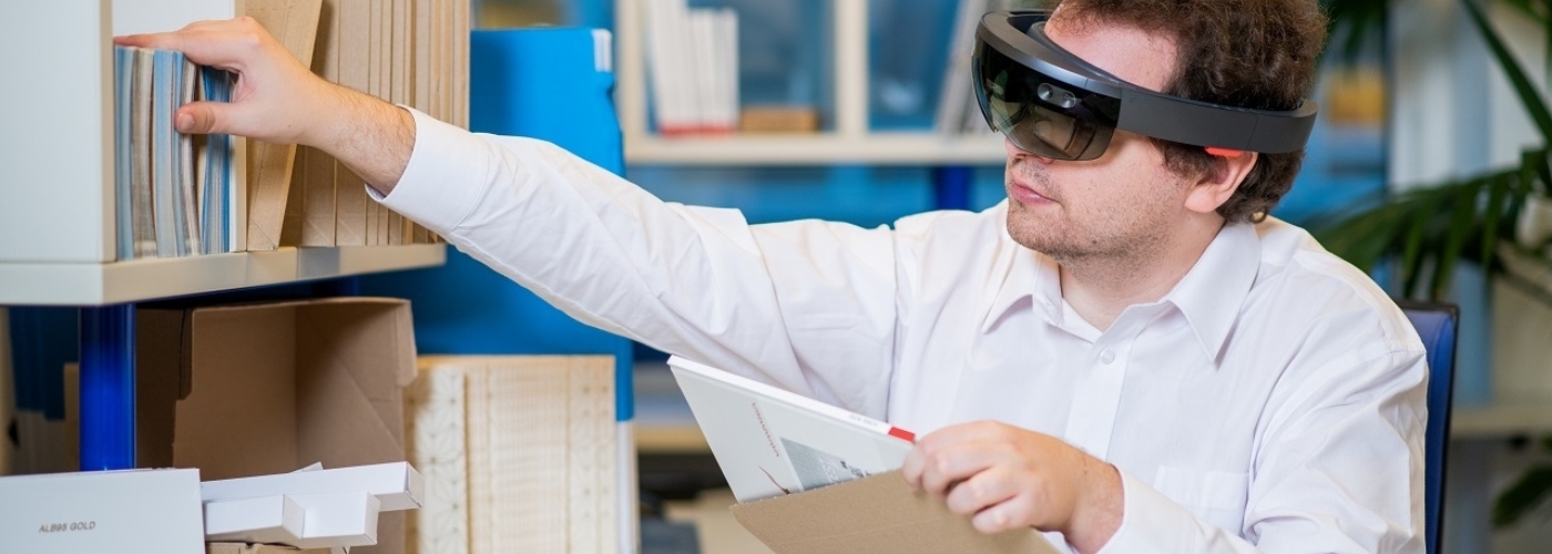 Mann hat eine dicke technische Brille auf und arbeitet an einem Schreibtisch