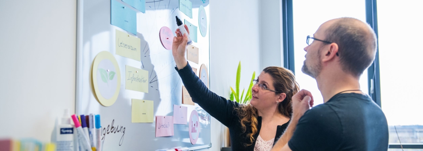 Zwei Menschen betrachten Post-It Wand