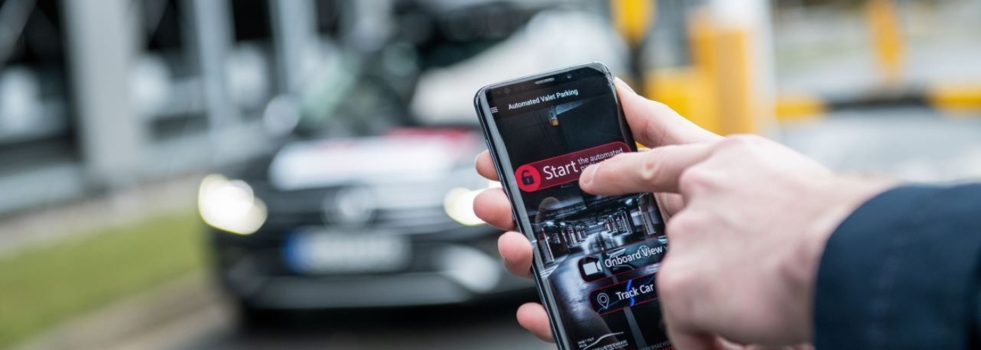 Ein Handy wir vor einem Auto stehend bedient