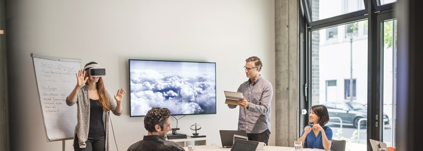 Personen in Raum mit Frau, die eine AR-Brille trägt