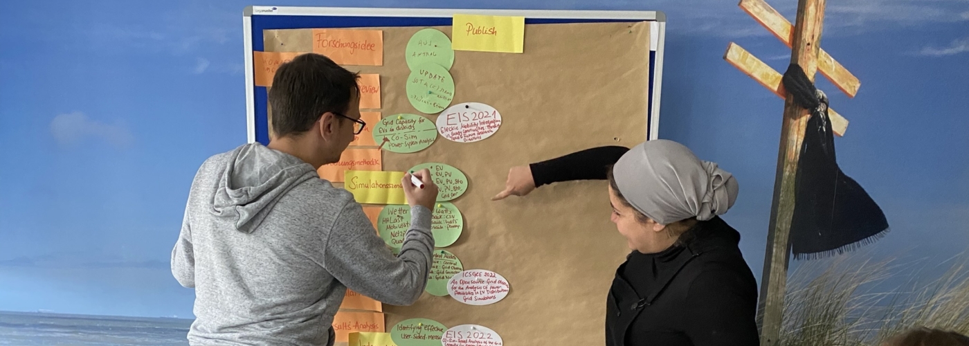 Personen stehen an Flipchart und füllen diese mit Post-Its