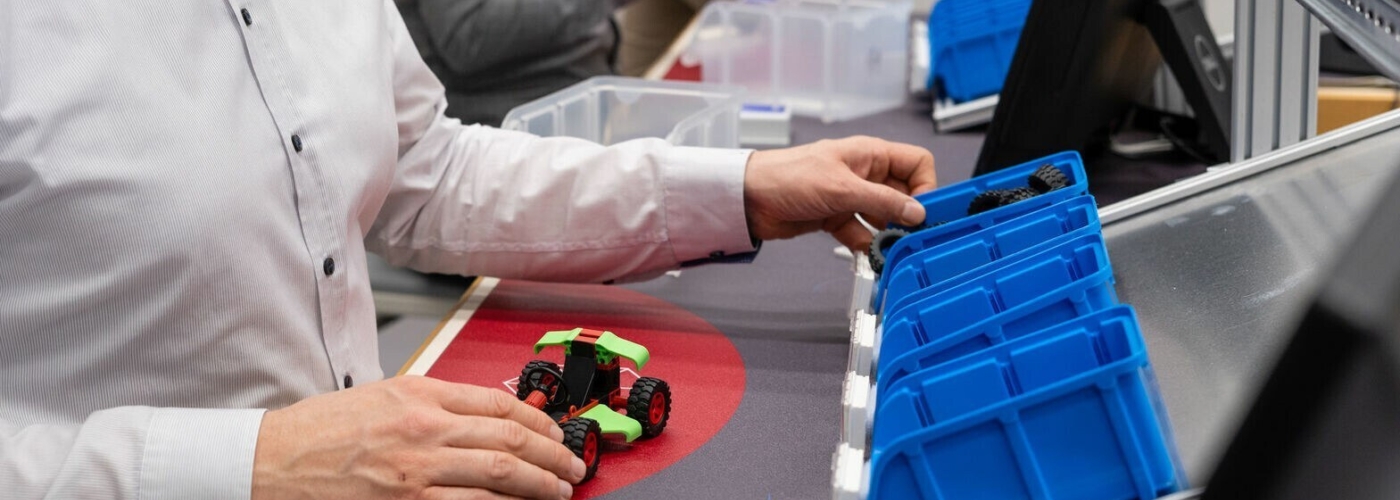 Person bastelt an kleinem Modellfahrzeug mit Rädern