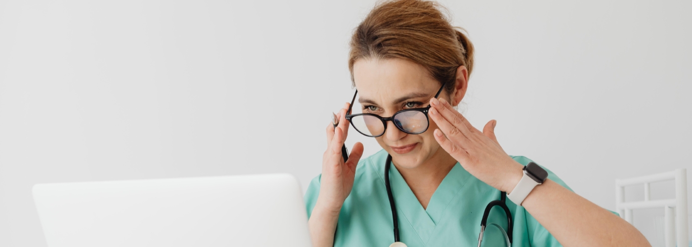 Frau aus medizinischem Beruf sitzt an Laptop