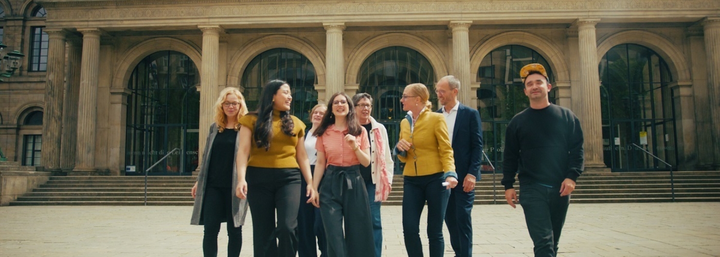 Eine Personengruppe läuft vor einem Gebäude