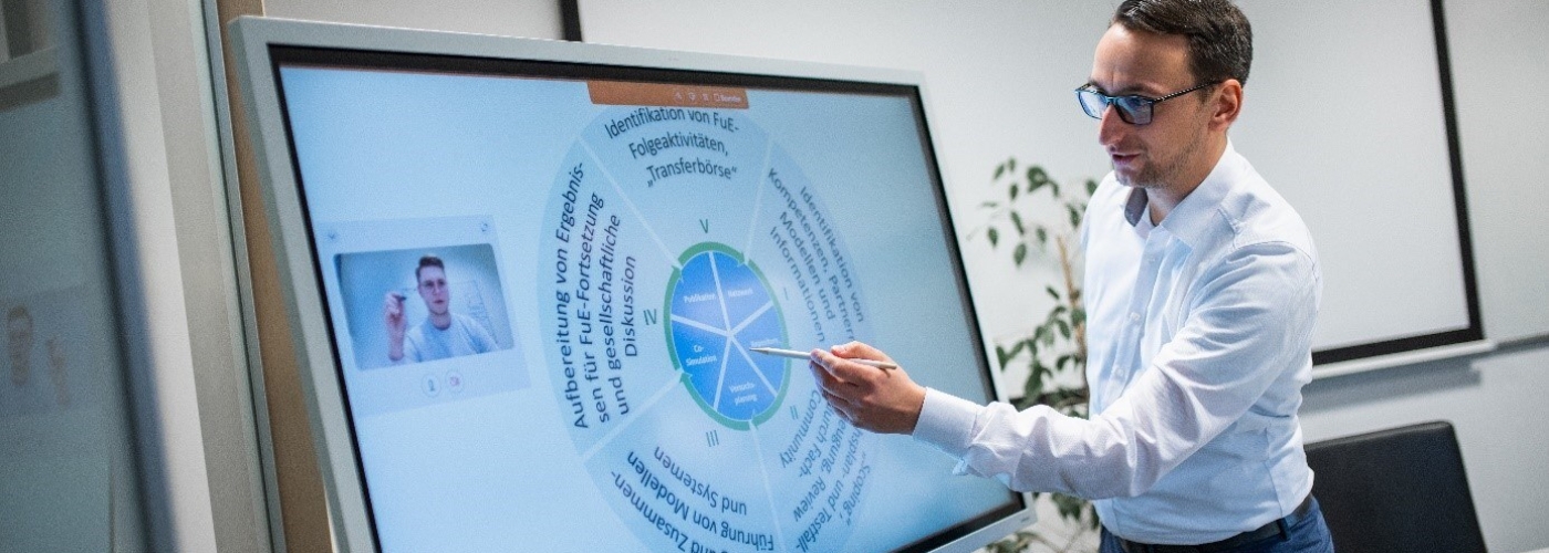 Mann zeigt etwas auf einem Bildschirm