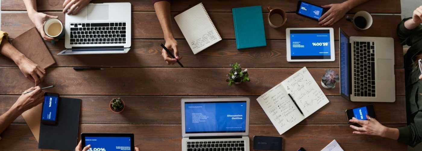 Konferenztisch an dem mehrere Personen mit Laptops zusammenarbeiten