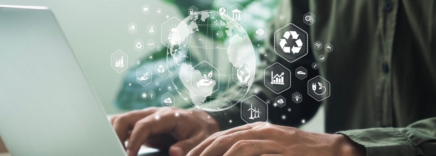 Über Händen auf einer Laptoptastatur schwebt eine Erde mit Symbolen zur Nachhaltigkeit.